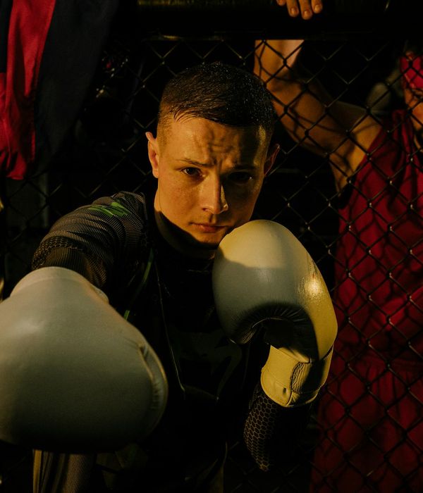 A man performing a controlled strength exercise in a dark room with purple light.